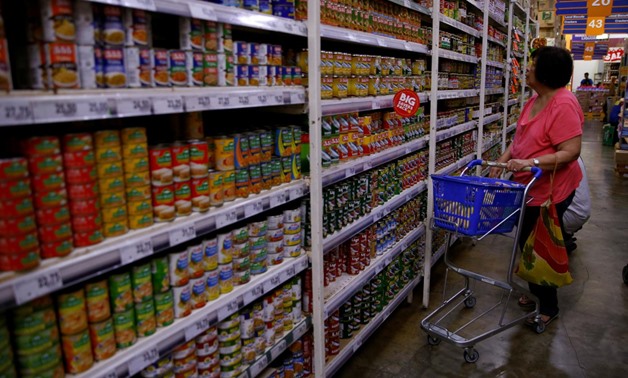 FILE - A woman scans the selection of canned goods at a grocery store in Makati City, Metro Manila, Philippines, September 19, 2018 - Reuters
