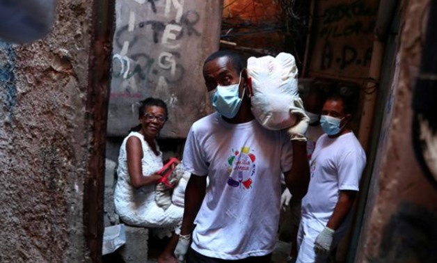 FILE PHOTO: A volunteer carries donated aid for poor families at the Rocinha slum as the coronavirus disease (COVID-19) outbreak continues in Rio de Janeiro, Brazil March 27, 2020. REUTERS/Pilar Olivares/File Photo