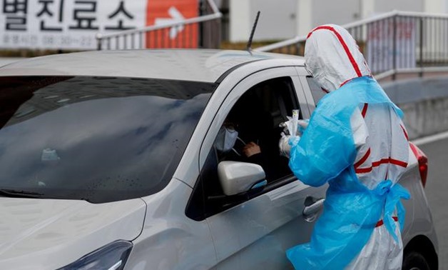FILE PHOTO: A medical staff member in protective gear prepares to take samples from a visitor at a 'drive-thru' testing center for the novel coronavirus disease of COVID-19 in Yeungnam University Medical Center in Daegu, South Korea, March 3, 2020. REUTER