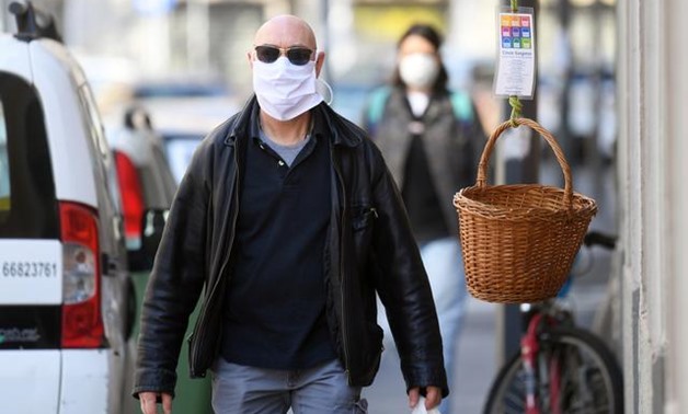 A man wearing a protective mask walks next to a basket of free food amid the coronavirus disease (COVID-19) outbreak, in Milan, Italy April 9, 2020. REUTERS/Daniele Mascolo
