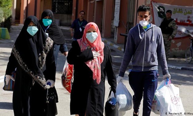 FILE - Women and a man wearing face masks in Iraq - Reuters