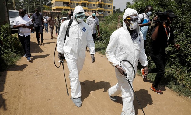 Kenyan health workers dressed in protective suits walk after disinfecting the residence where Kenya's first confirmed coronavirus patient was staying, in the town of Rongai near Nairobi, Kenya March 14, 2020. REUTERS/Baz Ratner