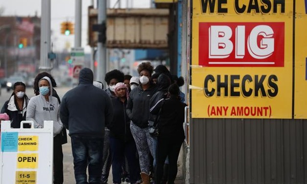 People wear face masks waiting outside a beauty salon and check cashing facility as the coronavirus disease (COVID-19) continues to spread, in the Highland Park section of Detroit, Michigan U.S., April 25, 2020. REUTERS/Shannon Stapleton
