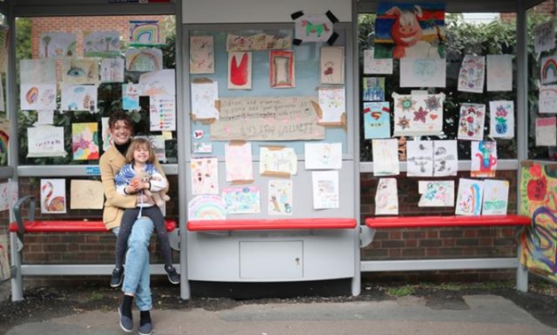 Sarah Lamarr and her 4 year old daughter, Rosie, who started a "Bus stop gallery" pose for a photograph at a bus stop with art work following the outbreak of the coronavirus disease (COVID-19), London, Britain, April 27, 2020. REUTERS/Hannah McKay
