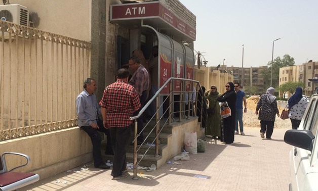 Egyptians are gathering in front of an ATM to withdraw money in the city of May 15, southern Cairo- Press photo.