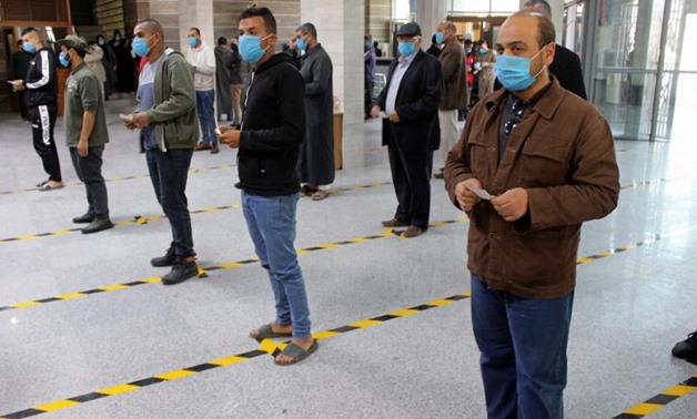 FILE - People wear protective masks, as part of precautionary measures against coronavirus disease (COVID-19), as they stand in a queue at a bank in Misrata, Libya March 22, 2020 - Reuters