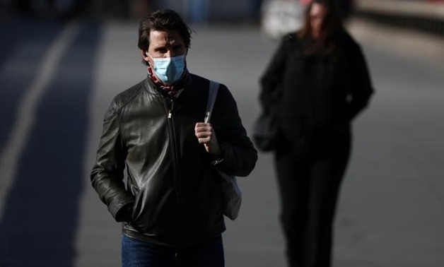 A man wearing a protective face mask walks along London Bridge following the outbreak of the coronavirus disease (COVID-19), London, Britain May 11, 2020. REUTERS/Simon Dawson