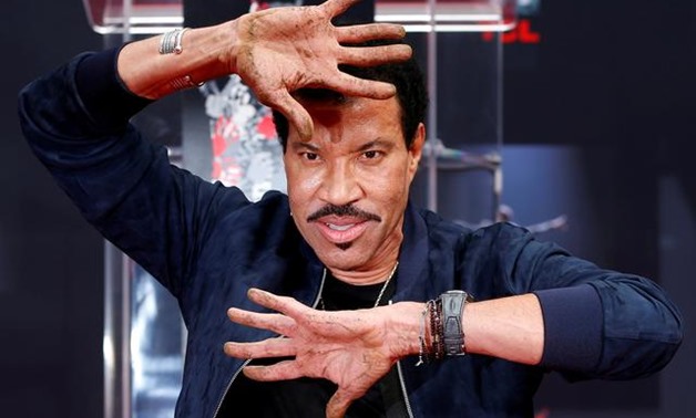 FILE PHOTO: Recording artist Lionel Richie shows his hands after placing them in cement during a ceremony in the forecourt of the TCL Chinese theatre in Los Angeles, California, U.S., March 7, 2018. REUTERS/Mario Anzuoni.