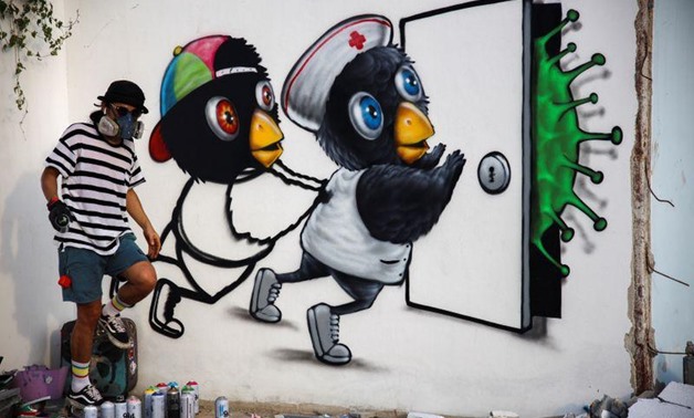 Mue Bon, a Thai street artist paints a mural depicting characters attempting to keep a virus at bay, in Bangkok, amidst an outbreak of the coronavirus disease (COVID-19) in Thailand, May 21, 2020. REUTERS/Juarawee Kittisilpa.