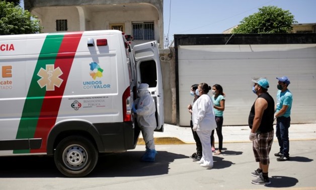 FILE PHOTO: Relatives of a man who died of the coronavirus disease (COVID-19) before being transferred to a hospital are seen near an ambulance transporting the body of their loved one, in Ciudad Juarez, Mexico May 26, 2020. REUTERS/Jose Luis GonzalezREUT