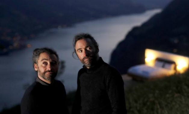 Swiss artists Frank and Patrik Riklin pose in front of the bedroom of their Zero-Real-Estate land art installation, as the outbreak of the coronavirus disease (COVID-19) continues, on an alp in front of the Churfirsten mountain range and Lake Walen near W