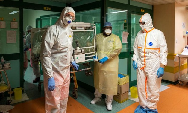FILE - Medical workers in protective suits transfer a coronavirus patient from the intensive care unit of the Gemelli Hospital to the Columbus Covid Hospital, which has been assigned as one of the new coronavirus treatment hospitals in Rome, Italy, March 