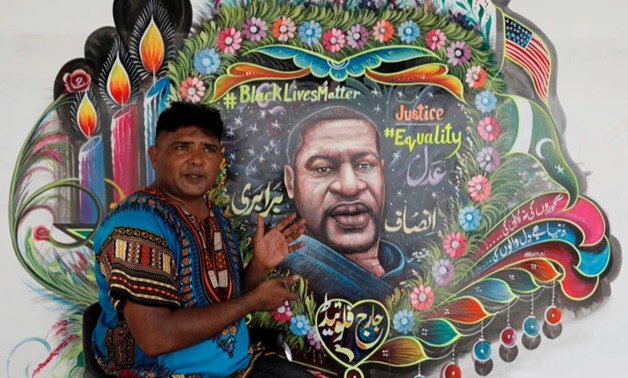 FILE PHOTO: Pakistani truck-art painter Haider Ali, 40, gestures as he speaks with Reuters next to a mural he painted, depicting George Floyd -  REUTERS/Akhtar Soomro - RC2W7H9U09L6/File Photo