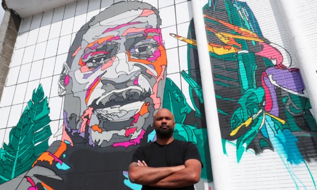 Belgian-Congolese street artist NovaDead, whose real name is Julien Crevaels, poses next to a giant mural paying tribute to George Floyd - Belgium June 18, 2020. REUTERS/Yves Herman