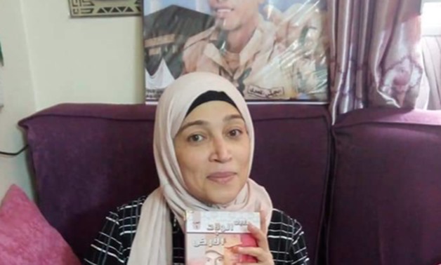 Mother of martyr Walid Sayed happily holding the dedicated book - ET