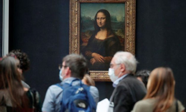 Media people, wearing protective face masks, stand in front of the painting "Mona Lisa" (La Joconde) by Leonardo Da Vinci at the Louvre museum in Paris as the museum prepares to reopen its doors to the public. Picture taken June 23, 2020. REUTERS/Charles 