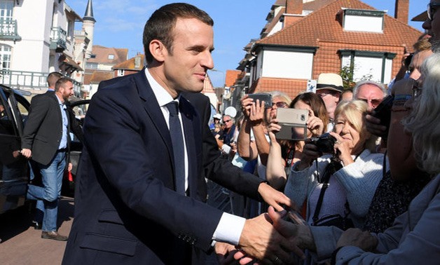 French President Emmanuel Macron (L) shakes hands with people outside the city hall where he votes in the second round parliamentary elections in Le Touquet, France, June 18, 2017. REUTERS