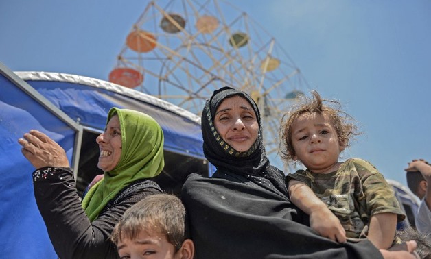 A displaced Iraqi family pose at a temporary camp in the compound of a hotel  - AFP/MOHAMED EL-SHAHED