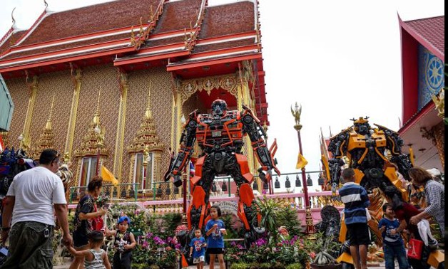 shows people enjoying giant metal statues inspired by the Transformers franchise, by Ban Hun Lek metalworks, at Wat Ta Kien Buddhist temple in Nonthaburi. - AFP