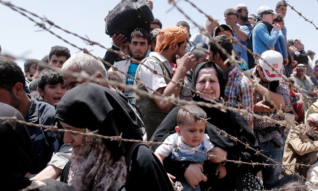 Syrian refugees wait on the Syrian side of the border near Sanliurfa, Turkey, June