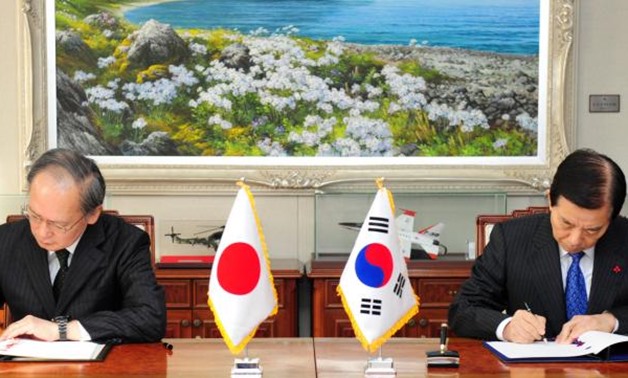 Han Min-koo and Japan's ambassador to South Korea Yasumasa Nagamine sign documents of general security of military information agreement - Defense Ministry/Yonhap via REUTERS