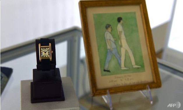 An engraved Cartier watch belonging to Jacqueline Kennedy Onassis and an original painting by the former first lady are displayed at Christie's in New York. (AFP)