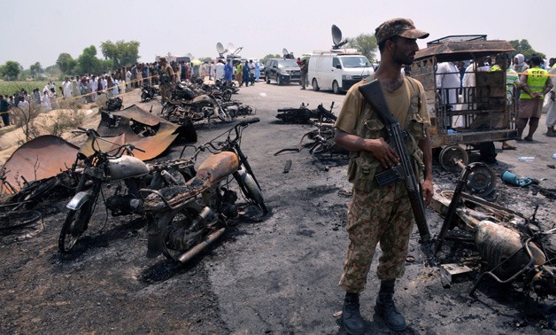 A soldier stands guard amid burnt out cars and motorcycles at the scene of an oil tanker explosion in Bahawalpur, Pakistan June 25, 2017. REUTERS/Stringer

