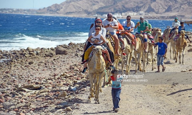 Tourists ride camels on the shores of the town of Dahab, in Egypt's southern Sinai