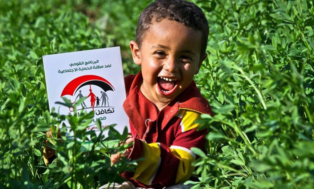 A boy laughs in a field- photo courtesy of Takamul and Karama Facebook Page