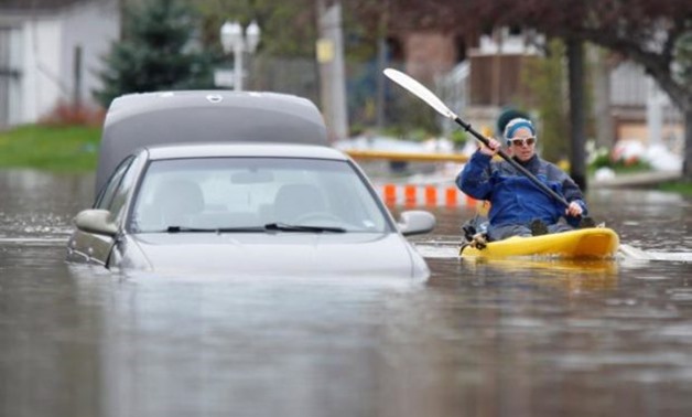 A woman paddles a kayak past an abandoned car on a flooded residential street in Gatineau, Quebec, Canada, May 4, 2017. REUTERS/Chris Wattie 