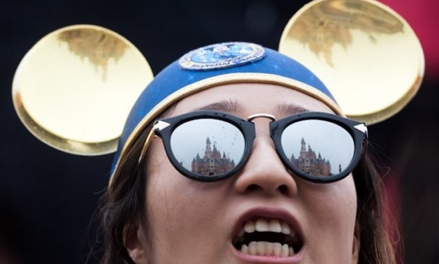 The Enchanted Storybook Castle is reflected in the sunglasses of a girl during the opening ceremony of the Shanghai Disney Resort in Shanghai on June 16, 2016. Disney did not expect that one of its offerings at the park would be a smash hit — turkey legs.