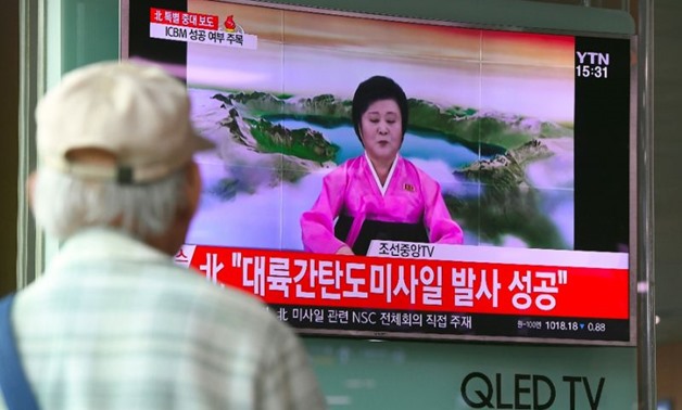 People watch a television news broadcast showing a North Korean announcer reading a statement on the country's new ICBM test, at a railway station in Seoul on July 4, 2017 (AFP Photo/JUNG Yeon-Je)
