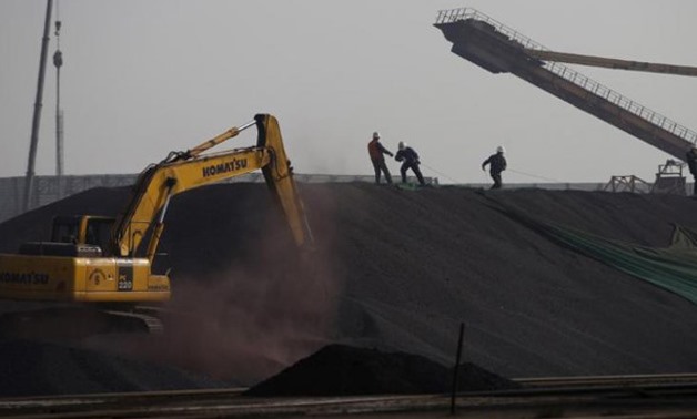 Labors work on a pile of iron ore at a steel factory- REUTERS-Kim Kyung-Hoon