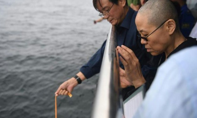This handout photo provided by the Shenyang Municipal Information Office shows late Nobel laureate Liu Xiaobo's wife Liu Xia praying as they bury Liu's ashes at sea off the coast of Dalian, Liaoning Province, on July 15, 2017