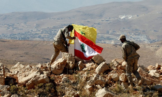 Hezbollah fighters put Lebanese and Hezbollah flags at Juroud Arsal, Syria-Lebanon border - REUTERS