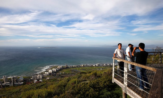 Tourists take pictures from a viewing platform overlooking Cape Town's Atlantic beachfront and Robben Island - REUTERS