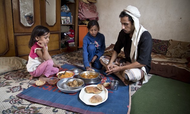 Walid, A Yemeni citizen and his two eldest daughters having a simple lunch of bread, rice and a traditional Yemeni vegetable dish, Salta. Photo: WFP/Marco Frattini