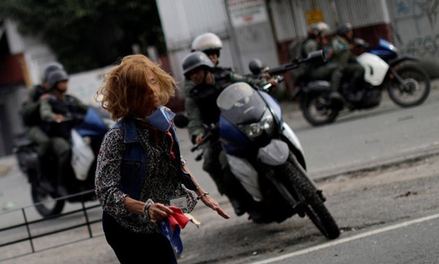 A woman runs away from riot security forces at a rally during a strike called to protest against Venezuelan President Nicolas Maduro's government in Caracas, REUTERS