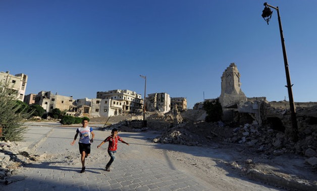 Boys run near a damaged site in the old city of Aleppo, Syria July 16, 2017. Picture taken July 16, 2017. REUTERS