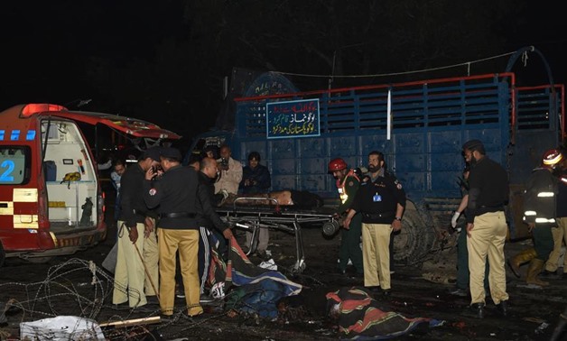 Pakistani policemen and volunteers move the bodies of victims at the site of a bomb explosion - press photo
