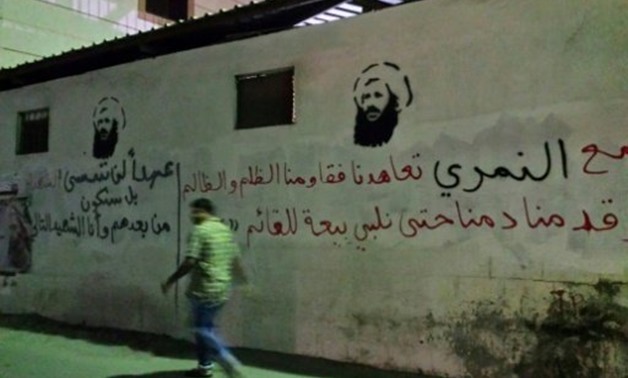 © AFP/File | A man walks past images of executed Shiite cleric Nimr al-Nimr on a wall in the Awamiya area in Saudi Arabia's Eastern province, in a picture taken in 2016
