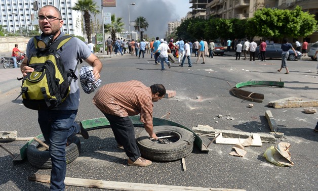 A supporter of Egypt's ousted president Mohamed Morsi tries to build a barricade as others run for cover during clashes with riot police as they try to disperse a pro-Morsi protest camp, on August 14, 2013 near Cairo's Rabaa al-Adawiya mosque. Egypt's Mus