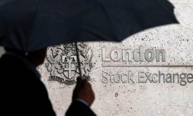 FILE PHOTO: A man shelters under an umbrella as he walks past the London Stock Exchange in London, Britain August 24, 2015.
Suzanne Plunkett/File Photo