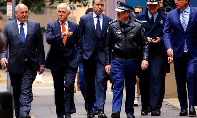 Australian Prime Minister Malcolm Turnbull walks with officials along a street before holding a media conference announcing Australia's national security plan to protect public places in central Sydney