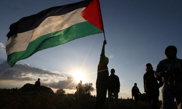 A demonstrator holds a Palestinian flag during a protest near the Israel-Gaza border fence, in the southern Gaza Strip December 21, 2018. (Reuters)