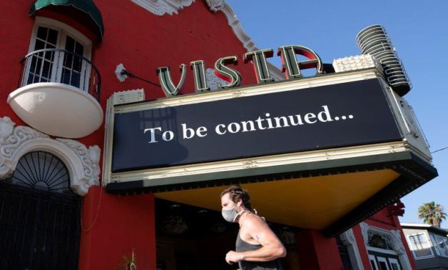  A person wearing a face mask jogs by the Vista theatre during the outbreak of the coronavirus disease (COVID-19), in Los Angeles, REUTERS/Mario Anzuoni.