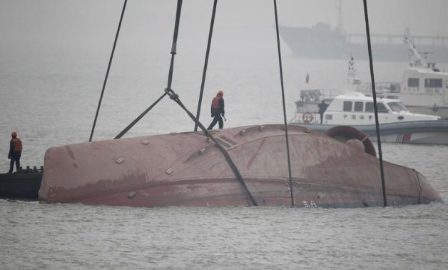 A rescue worker searching for survivors stands on top of a tug boat that sank in the Yangtze River, near Jingjiang, Jiangsu province January 16, 2015. REUTERS/ Aly Song