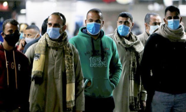 FILE - Men in protective masks wait for the train at a metro station in Cairo – Reuters