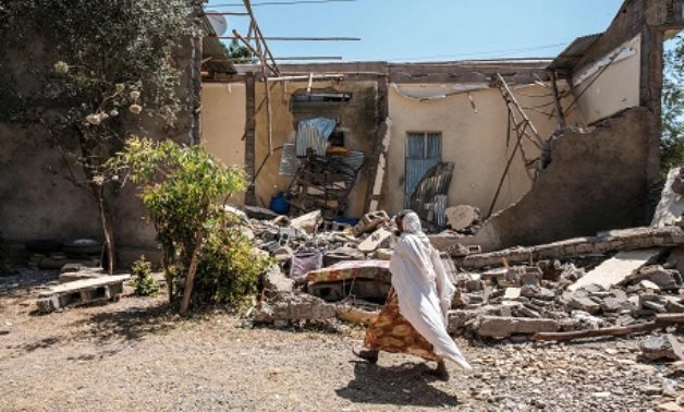 A woman walks in front of a damaged house which was shelled as federal-aligned forces entered the city, in Wukro, north of Mekele, on March 1, 2021 AFP