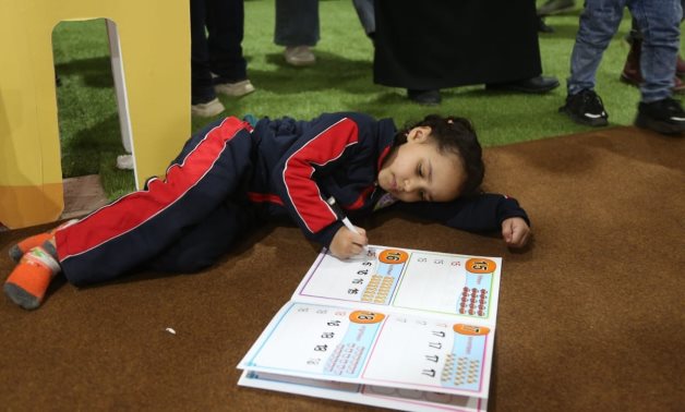 A girl draws in a drawing book at the 54th edition of Cairo International Book Fair – Egyptian Ministry of Culture